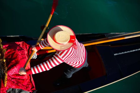 Venezianischer Gondoliere mit Hut und typischem weiß-rotem Kleid beim Rudern auf der Gondel auf dem Canal Grande in Venedig in Italien in Europa