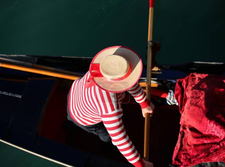 Foto de Gondolero con un sombrero remando una góndola en un canal de Venecia fotografiado desde arriba - Imagen libre de derechos