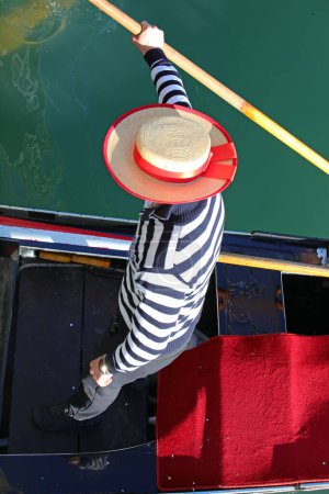 Photo for Gondolier with an hat rowing a gondola in a Venice canal photographed from above - Royalty Free Image