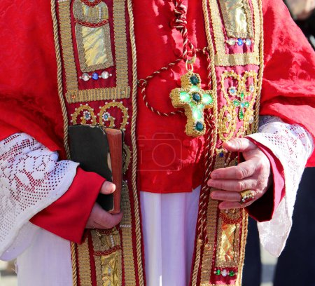 Priester im feierlichen Soutanensegen mit der Bibel in der Hand während der heiligen Messe