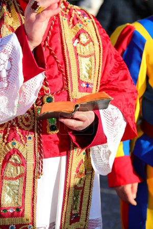 Téléchargez les photos : Prêtre en vêtements rouges Bénédiction avec la Garde suisse à côté - en image libre de droit