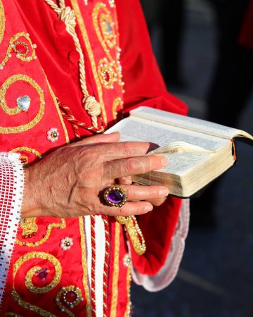 Téléchargez les photos : Bible dans les mains de l'évêque avec un anneau avec une pierre précieuse alors qu'il donne la bénédiction aux fidèles pendant le rite religieux - en image libre de droit
