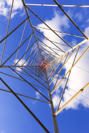 Téléchargez les photos : Pylône haut avec câbles haute tension pour le transport d'électricité et de nuages blancs sur le ciel bleu - en image libre de droit