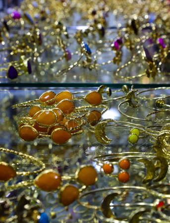 muchas pulseras de oro y anillos de varias formas con piedras de colores para la venta en el escaparate de la joyería
