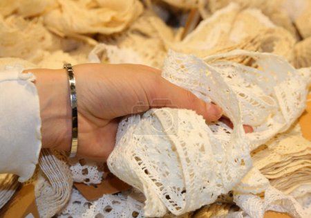 mano de una joven tocando la tela bordada con encaje en una sastrería artesanal