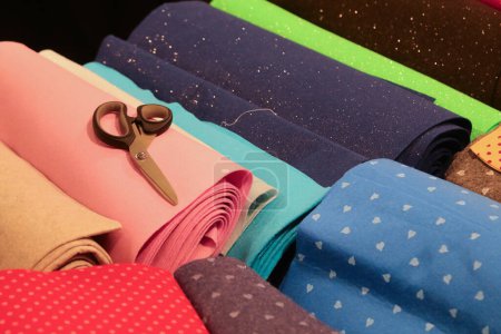 Téléchargez les photos : Ciseaux de tailleur et de nombreux tissus colorés en coton et feutre à vendre sur le comptoir dans la boutique de couture et de draperie - en image libre de droit