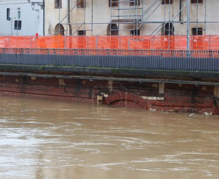 Straßenbaustelle mit orangefarbenem Schutznetz zur Verstärkung des Flussufers bei vollem Hochwasser in der Stadt