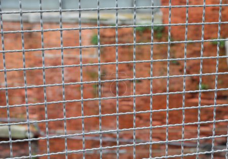 Foto de Valla de metal que separa la frontera y la pared de ladrillo de la penitenciaría fuera de foco en el fondo - Imagen libre de derechos