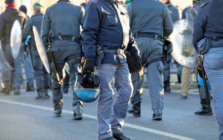 Photo for Many policemen in riot gear with protective helmet and truncheons during the protest demonstration in the city - Royalty Free Image