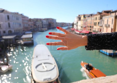Téléchargez les photos : Cinq doigts de la main de la jeune fille avec des ongles avec vernis à ongles rouge et le Grand Canal à Venise ITALIE - en image libre de droit
