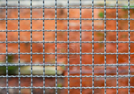 metallic border separation fence and the brick wall of the penitentiary out of focus in the background