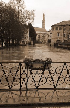 Photo for FURO Bridge and under the swollen RETRONE River during the flood in the city of Vicenza in Italy with vintage sepia  toned - Royalty Free Image