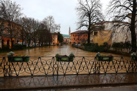Flowerpots on the FURO Bridge and under the swollen RETRONE River during the flood in the city of Vicenza in Northern Italy due to climate change