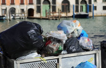 Varias bolsas de basura de residuos sólidos en un contenedor sobrecargado en la ciudad
