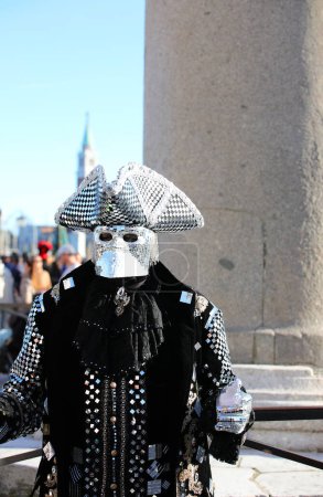 Foto de Venecia, VE, Italia - 13 de febrero de 2024: Hombre enmascarado con un traje original hecho de tela fina y muchos espejos que reflejan la luz en el Carnaval de Venecia - Imagen libre de derechos