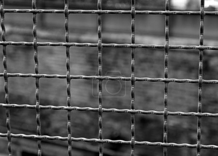 Barres de fer séparent la prison du mur en arrière-plan avec des tons très sombres pour un effet dramatique noir et blanc