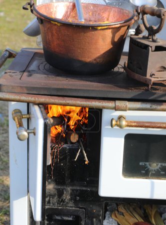 Alte holzbeheizte Küche mit angezündetem Feuer und darüber ein Kupferkessel zum Kochen