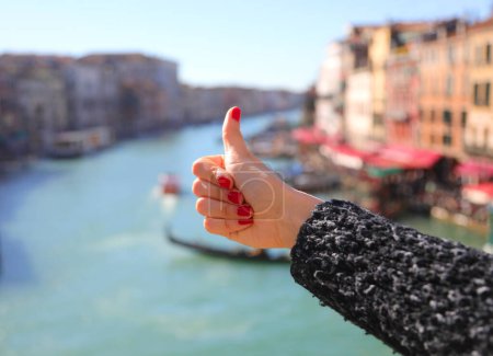 Thumb up ok sign of hand of young Girl with nails with nail polish and grand canal in venice in ITALY