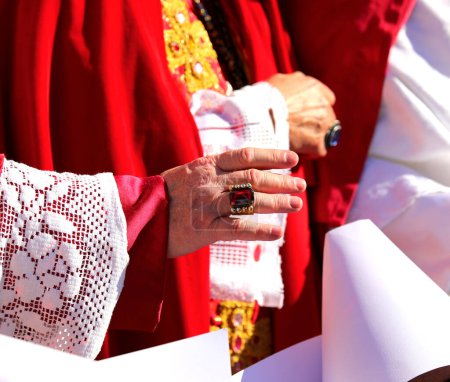 Obispo en traje religioso rojo bendice a los fieles con la mano y el anillo grande