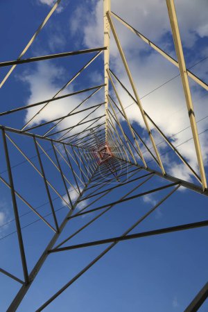 high pylon with high voltage cables for the transport of electricity and white clouds on the blue sky