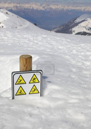 señal de precaución peligro de deslizamiento y caída cerca de barranco con nieve fresca blanca en las montañas