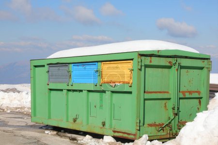 container in the outdoor recycling center for the separate collection of waste and white snow in winter