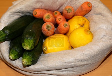 Photo for Bag of organic fruits and vegetables zucchini carrots and lemon for sale at the market - Royalty Free Image