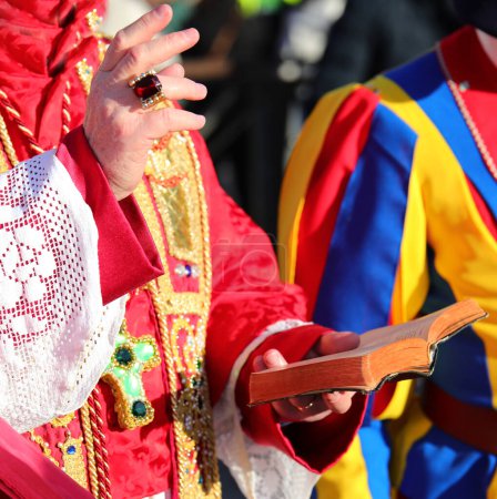 Hand mit Ring des Erzbischofs mit klerikalem Gewand, der während der heiligen Messe die Bibel der Heiligen Schrift hält