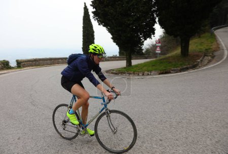 jeune cycliste avec des pédales de casque de protection en montée sur un vélo de course pendant la course cycliste dans les montagnes