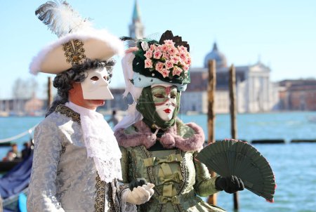 Photo for Venice, VE, Italy - February 13, 2024: couple with Venetian Mask at the Venice Carnival and adriatic sea on background - Royalty Free Image