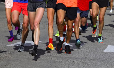 piernas de muchos corredores con zapatillas deportivas durante la carrera a pie en la ciudad