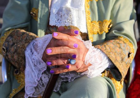 intertwined hands of people with purple malt nails and ancient noble clothes