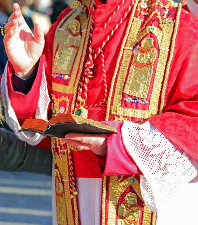 Erzbischof in klerikaler Kleidung mit der Bibel der Heiligen Schrift während der heiligen Messe