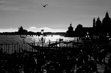 crowd of people in Venice backlit in black and white with unrecognizable faces and Venetian lagoon