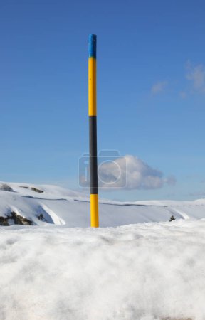 colorido puesto de advertencia de nieve durante las nevadas en las montañas en invierno