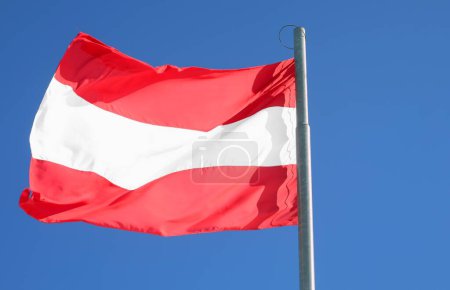 Austria flag with red and white stripes on background of the blue sky