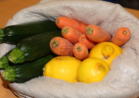 Photo for Bag of organic fruits and vegetables zucchini carrots and lemon for sale at the local market - Royalty Free Image