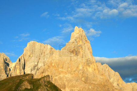 Cimon della Pala a mountain in the Italian Dolomites glows with warm orange hues at sunset with the natural phenomenon of Enrosadira and blue sky