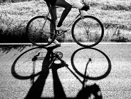 Silueta de ciclista con bicicleta de carreras en la carretera en blanco y negro con tonos muy oscuros