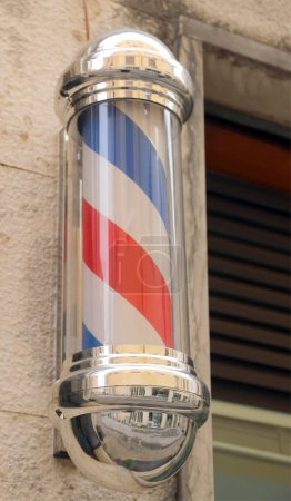 rotating barber shop sign with spiral stripes outside a traditional business