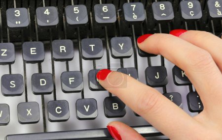 Sekretärs rotpolierte Fingernägel tippen auf den Tasten einer alten Schreibmaschine