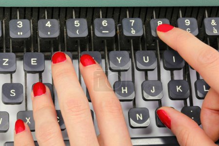 Foto de Uñas pulidas rojas de secretaria femenina escribiendo en las llaves de una máquina de escribir - Imagen libre de derechos