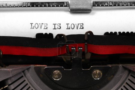 LOVE IS LOVE handwritten in black ink on white paper with an antique typewriter symbolizing universal and boundless love