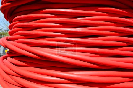 Bobinas de cable eléctrico rojo para alta tensión durante la instalación de infraestructura eléctrica