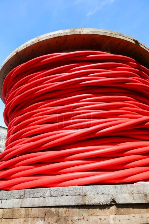 Carrete de cable eléctrico aislado rojo grueso para alto voltaje durante la colocación de infraestructura eléctrica