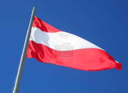 Large Austrian flag with red and white stripes waving in Austria ner the border