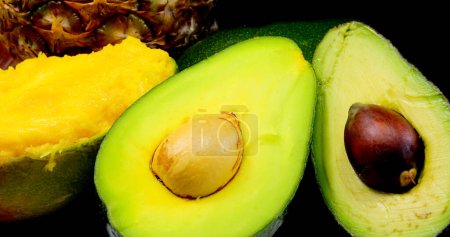 avocados halved with large seed ideal for making guacamole sauce and the pulp of the juicy mango