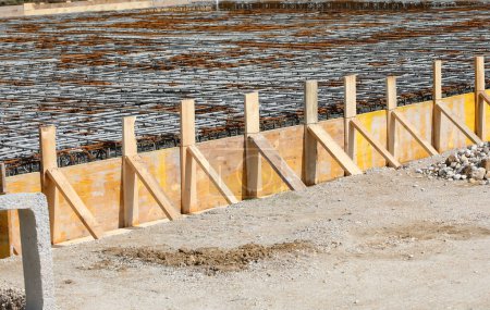 Téléchargez les photos : Coffrage de construction fait avec des planches de bois lors de la pose de ciment pour faire fondation du bâtiment sur le chantier de construction sans travailleurs - en image libre de droit