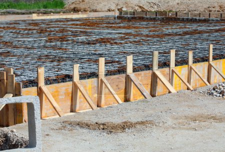 Téléchargez les photos : Coffrage réalisé avec des planches de bois jaune lors de la pose de ciment pour faire la fondation du bâtiment sur le chantier de construction sans travailleurs - en image libre de droit