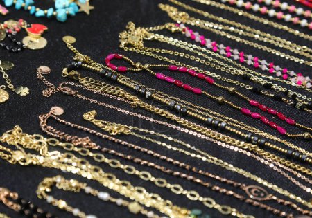 Halsketten und Armbänder und Fußkettchen für Frauen aus goldenem metallischem Material mit Edelsteinen oder Perlen und Anhängern zum Verkauf im Geschäft